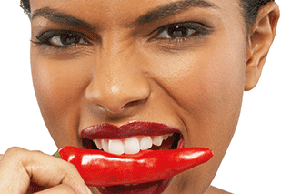A woman biting into a chilli pepper