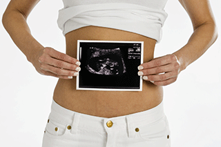 A pregnant woman holding an ultrasound scan picture